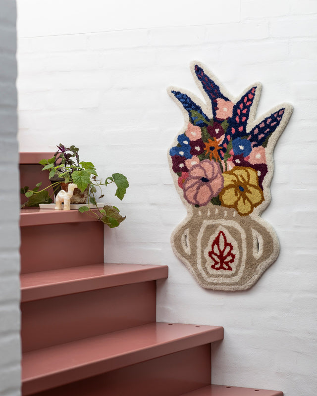 Blumenvasen-Teppich Flower Vase an einer weiß gestrichenen Ziegelwand neben einer rostroten Treppe