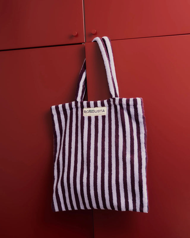 Weinrot und lavendelblau gestreifte Tote Bag hängt am Griff eines roten Schranks