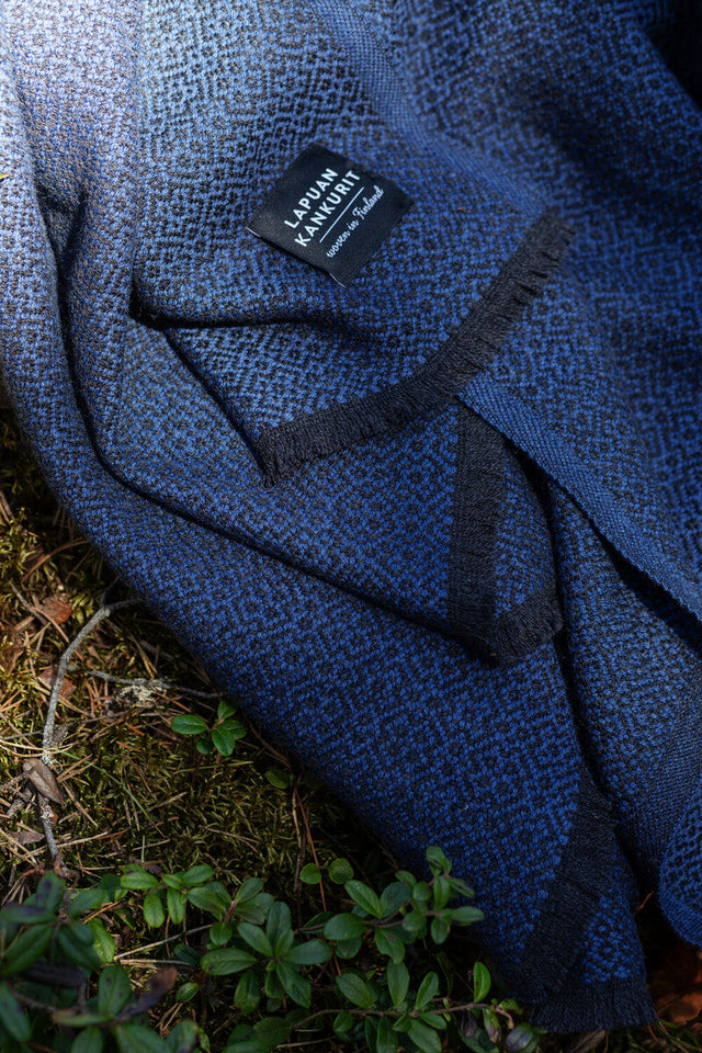 KOLI Merino-Wolldecke in Schwarz-Blau, über ein Sofa gelegt