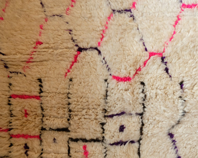 Nahaufnahme des hochflorigen Gewebes, die einzelnen Wollfäden in Weiß, Pink und Violett sind gut zu erkennen.