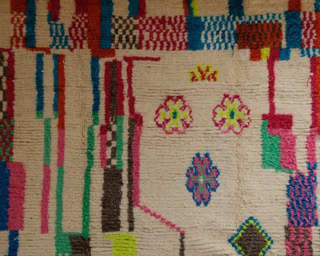 Detail mit drei Blumen in Pink, Gelb und Blau zwischen bunten Streifen