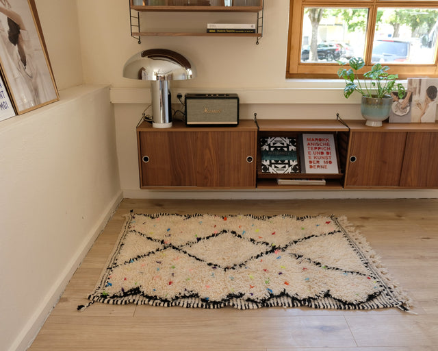 Kleiner Beni Ourain MINI DOTTIE 1,00 x 1,50 m im Raum: cremeweißer Flor mit schwarzen Rauten und bunten Punkten