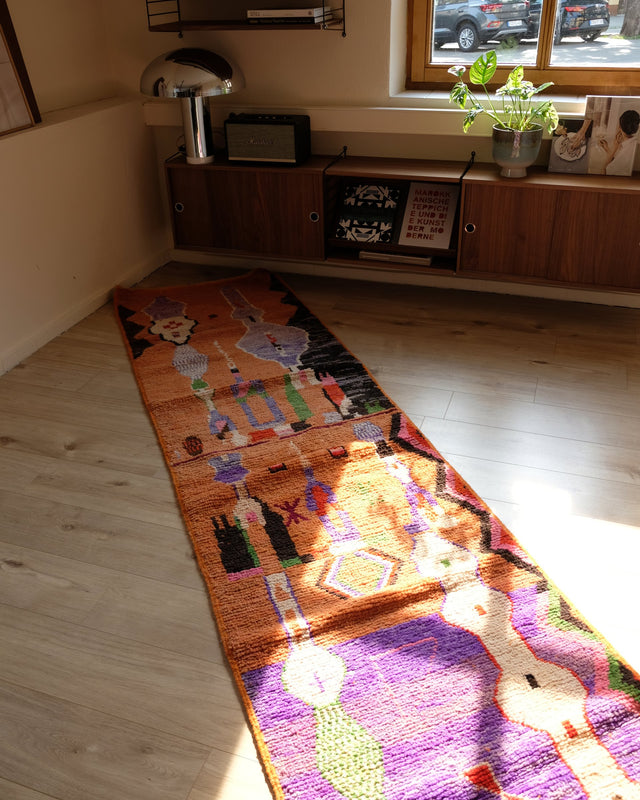 Langer bunter Läufer in Orange und Lila vor einem Sideboard aus Holz, im Sonnenlicht