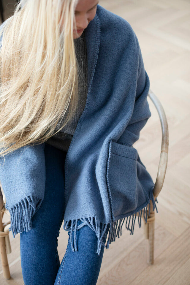Blonde Frau trägt den UNI POCKET Wollschal in Rainy Blue