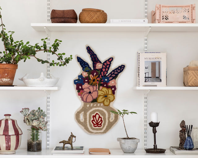 Teppich Flower Vase an einer weißen Wand zwischen Regalbrettern mit Pflanzen, Körben und Keramik