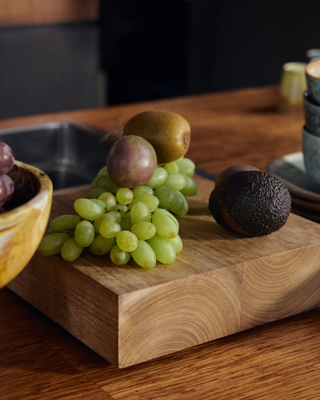Teakholz-Sockel mit Weintrauben, Kiwi und Avocado auf einer Küchenarbeitsplatte