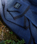 KOLI Merino-Wolldecke in Schwarz-Blau, über ein Sofa gelegt