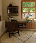 Beni Ourain CLASSIC ONE mit braunem Ledersessel vor Sideboard und Fenster