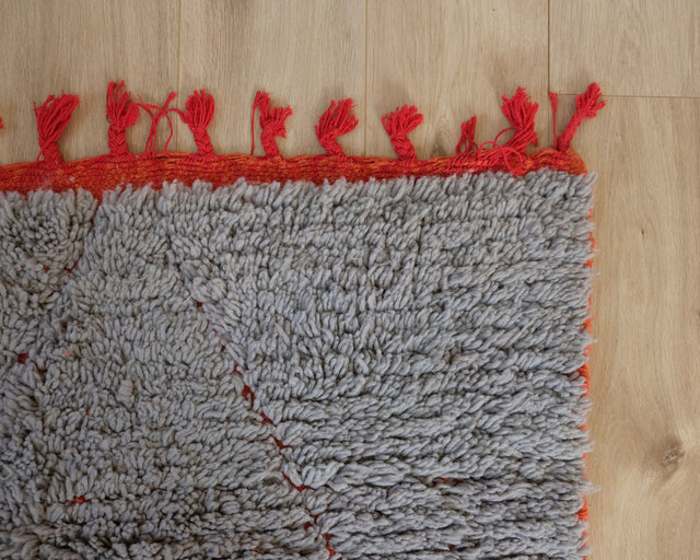 Teppichecke mit roter Einfassung und roten Quasten