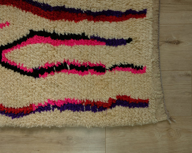 Wellige Linien in Pink, Rot, Lila und Schwarz am Teppichrand