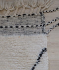 Detail: Kelimrand mit schwarz-weißem Muster und zweifarbigen Kordeln an der Ecke