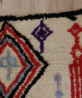 Nahaufnahme einer Raute mit graublauem Kreuz in der Mitte, schwarzer Rand und lila Motiv