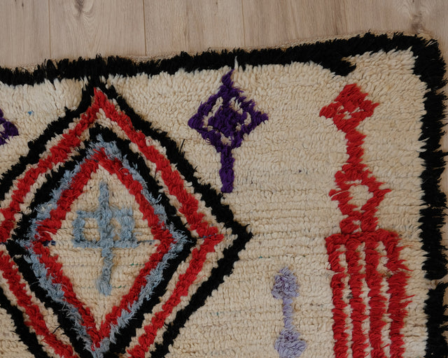 Nahaufnahme einer Raute mit graublauem Kreuz in der Mitte, schwarzer Rand und lila Motiv