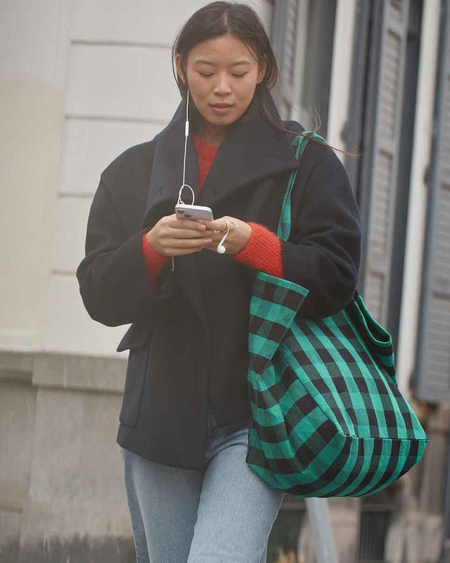 Frau im dunklen Mantel mit der Tote Bag ELISA in Big Vichy Green über der Schulter auf der Straße