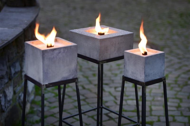 Nahaufnahme: Alle drei eckigen Betonfeuer auf Ständern  mit entzündeter Flamme.