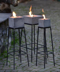Alle drei eckigen Betonfeuer auf Ständern  mit entzündeter Flamme.